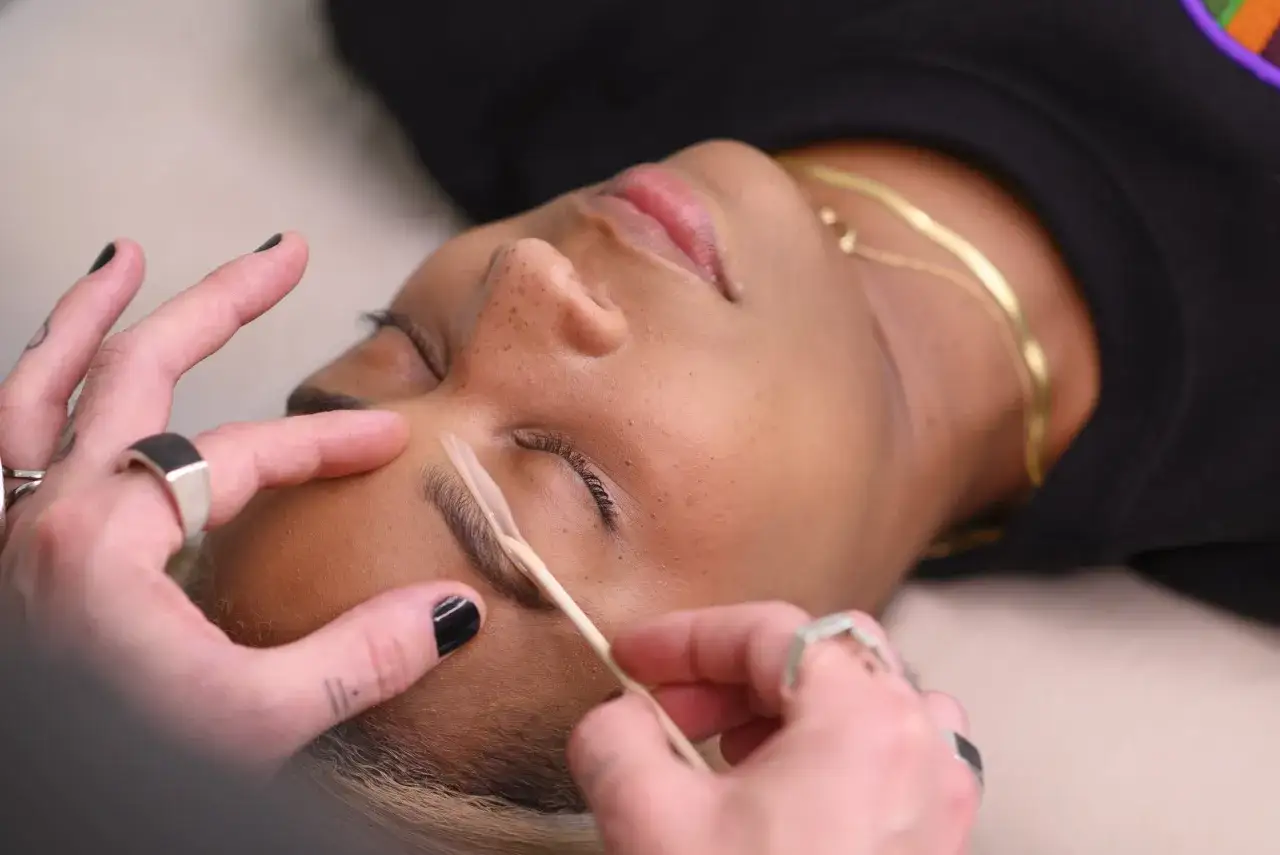 Manos aplicando cera en cejas. ¡Cuidado! depilar cejas con cera es malo para la piel.