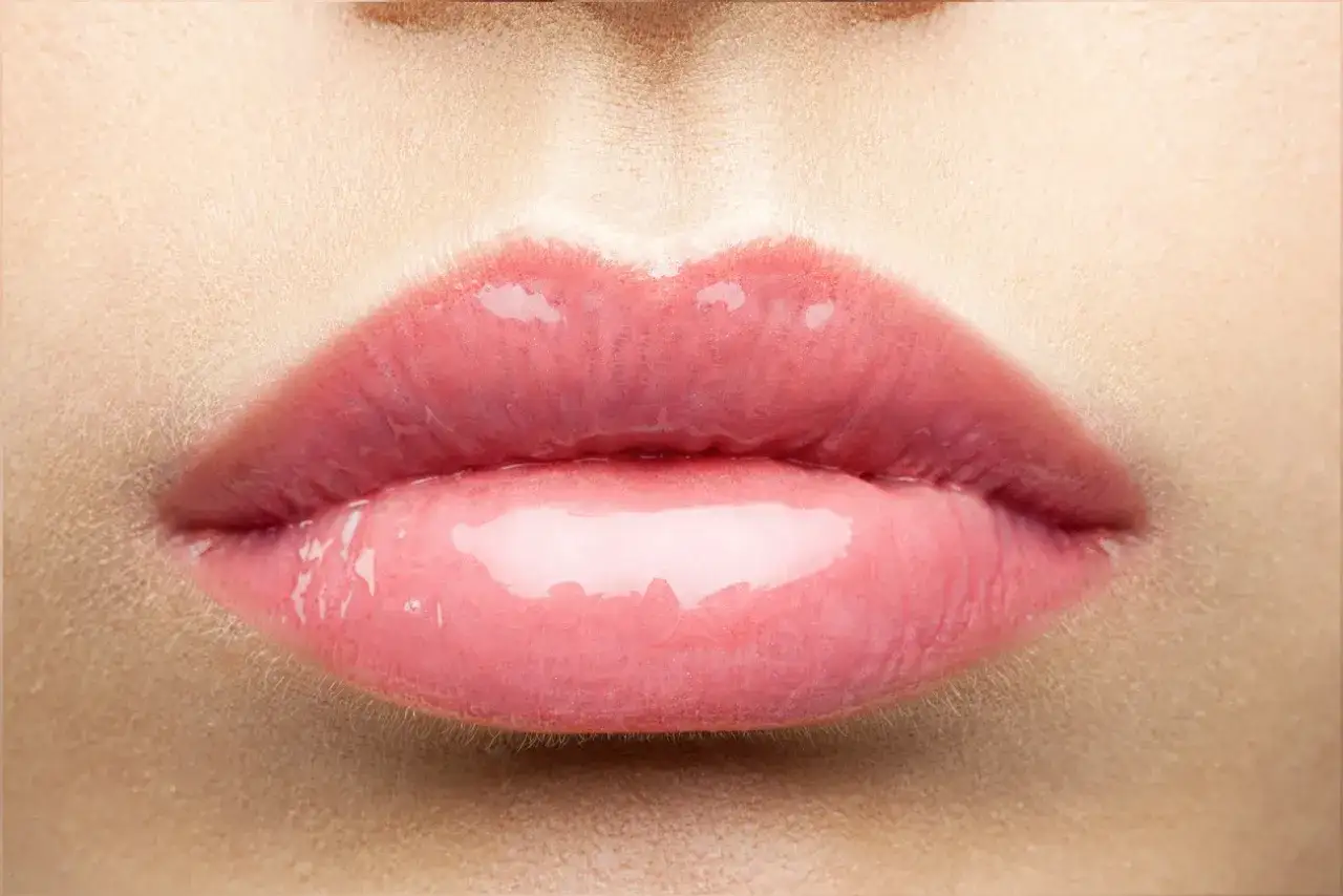 Labios rosados y brillantes, con un toque de cereza, que invitan a un dulce beso.