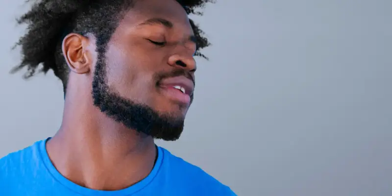 Hombre con perilla barba y ojos cerrados, disfrutando un momento de paz.